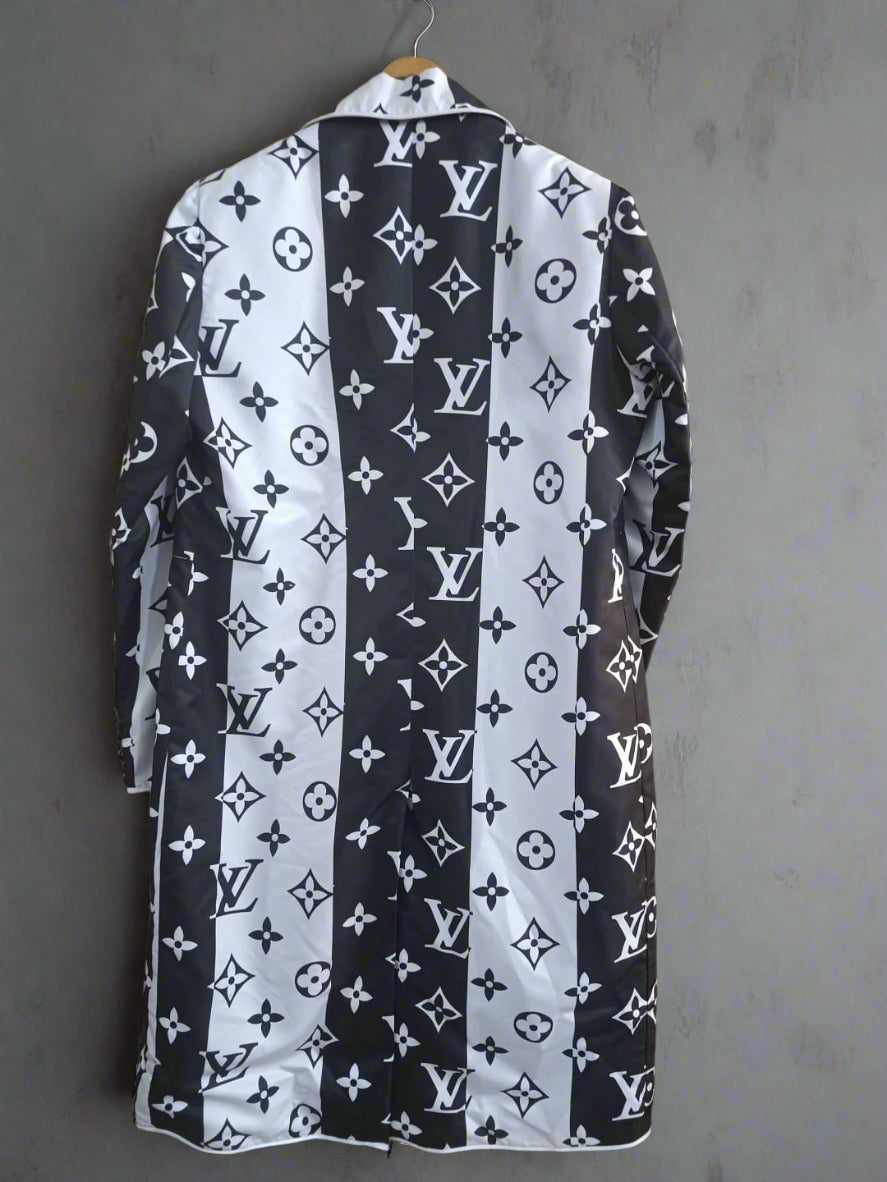 Black and white patterned long coat with brand logo against a gray wall