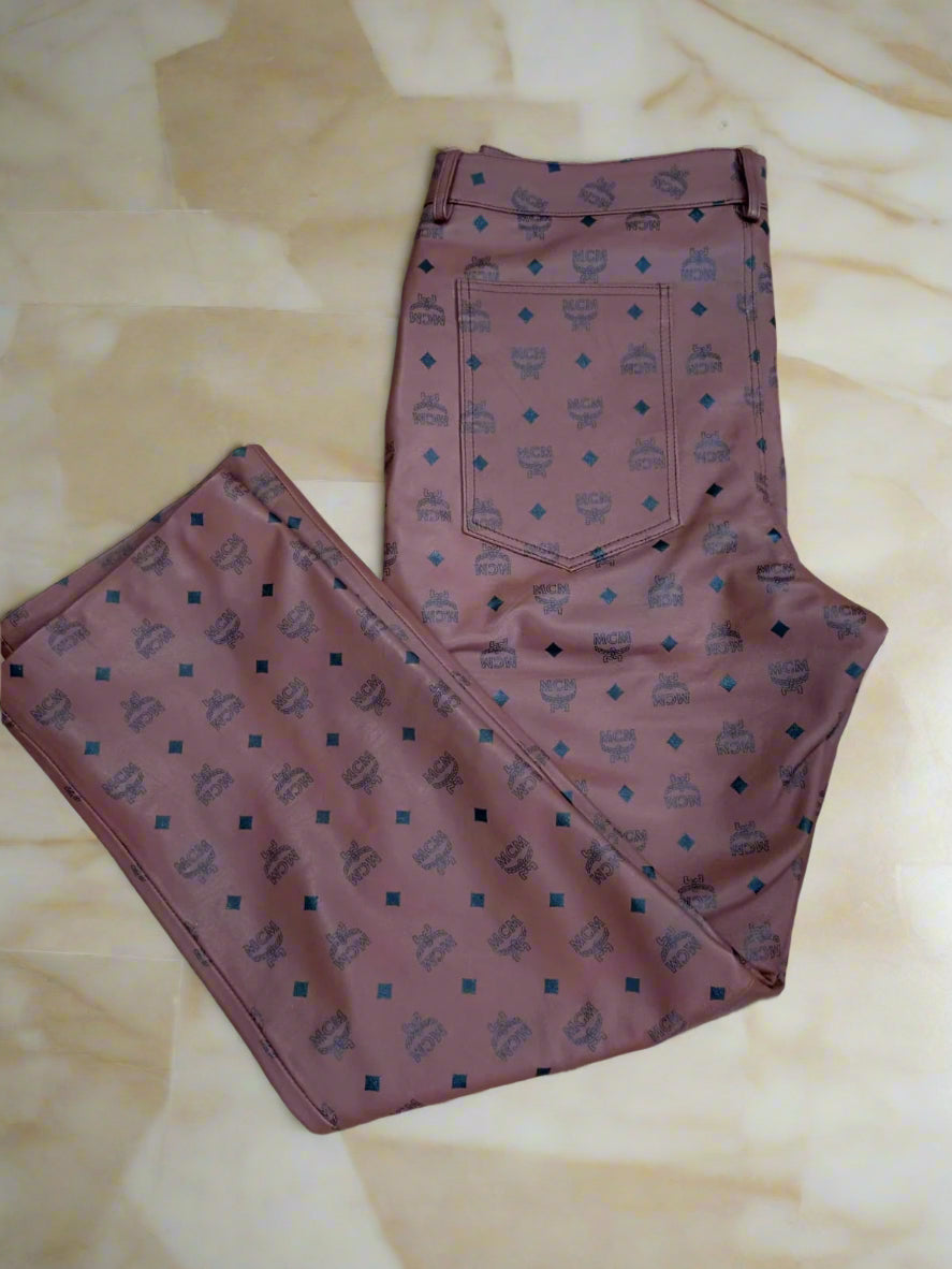 Folded brown mcm leather pants with a pattern on a marble floor
